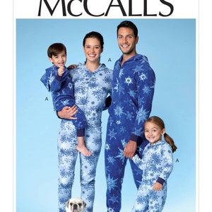 Puede incluir: Un conjunto de pijama a juego para toda la familia con un patrón de copo de nieve en azul y blanco. El conjunto incluye un mono con capucha para adultos y niños, y una chaqueta con capucha para perro. El patrón incluye el texto "M7518".