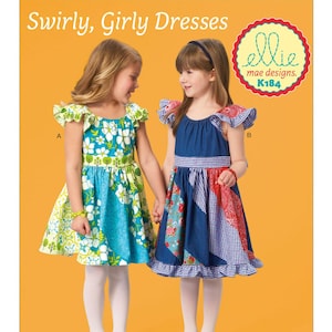 May include: Two young girls holding hands, wearing colorful dresses. One dress is blue and green with a floral pattern, the other is denim with patchwork details. The image has the text "Swirly, Girly Dresses" and "ellie mae designs. K184".
