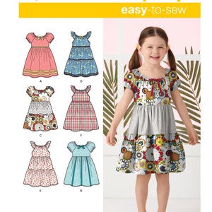 May include: Simplicity sewing pattern number 2377, easy-to-sew, for a girl's dress. The pattern includes six different styles of dresses, including a pink dress with a bow, a blue and white floral dress, a multi-colored floral dress, a red and white plaid dress, a pink floral dress, and a blue and white striped dress.