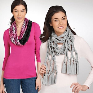 May include: Simplicity sewing pattern 1311 featuring two scarf designs. Scarf A is a pink, black, and white chevron infinity scarf with black trim. Scarf B is a grey knotted scarf with silver-toned rings and fringe ends. Text includes IT'S SO easy IT'S Simplicity.