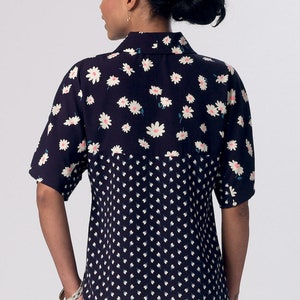 May include: A navy blue and white short-sleeved blouse with a daisy print on the top half and a smaller white dot print on the bottom half.