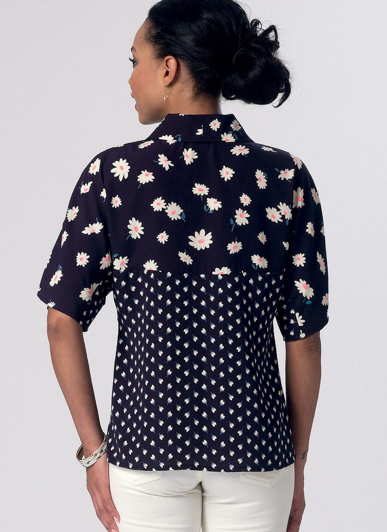 May include: A navy blue and white short-sleeved blouse with a daisy print on the top half and a smaller white dot print on the bottom half.