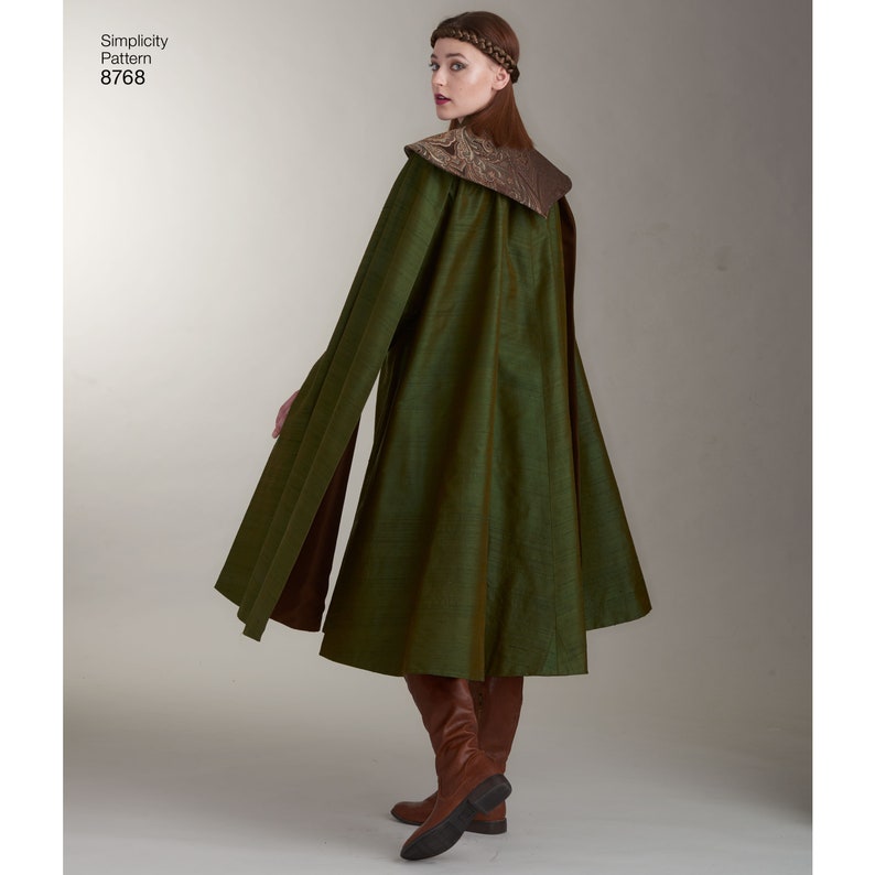May include: A long green cape with a brown collar and a brown belt. The cape is made of a soft, flowing fabric and has a long train. The model is wearing a brown headband.
