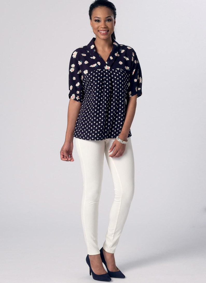 May include: A woman is wearing a black and white patterned blouse with a collar and white pants. She is wearing navy blue heels.