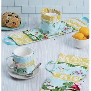 Puede incluir: Un patrón de costura para un calienta tazas y un porta bolsitas de té. El patrón se llama Simplicity S9511. El calienta tazas está hecho de una tela floral amarilla y azul. El porta bolsitas de té está hecho de una tela floral amarilla y azul con un bolsillo para bolsitas de té. El patrón incluye instrucciones para hacer ambos artículos.