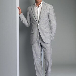May include: A striped suit in a light blue and white color combination. The suit jacket has a single button closure and the pants have a straight leg.
