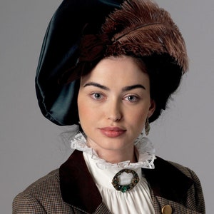May include: A woman wearing a dark green hat with a large brown feather, a white ruffled collar, and a brown and tan tweed jacket. A decorative brooch with a green stone is pinned to the collar.
