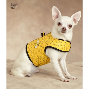 May include: A small white dog wearing a yellow quilted vest with a black trim and a bee applique. The vest has a diamond pattern with small spiral designs. The dog is sitting on a neutral-colored surface. The text "Simplicity Pattern 2393" is in the upper left corner.