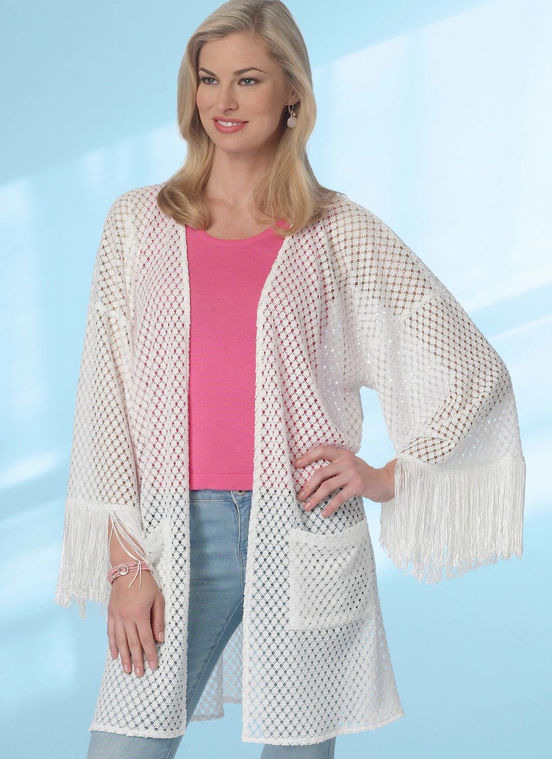 May include: White crochet cardigan with fringe detailing on the sleeves and hem. The cardigan has a loose fit and a pocket on the front.