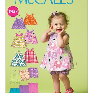 Peut inclure: Patron de couture McCall's pour robes et shorts de bébé. Le patron comprend différents styles de robes avec différents imprimés et une sélection de shorts. L'image montre un bébé portant une robe et un short à imprimé éléphant rose, avec des sandales roses.