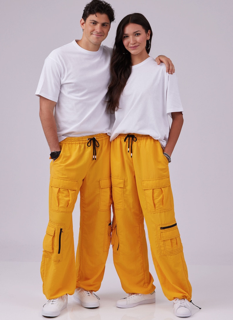 May include: Two people wearing white t-shirts and matching yellow cargo pants with black drawstrings. The pants have multiple pockets with zippers.