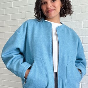 Peut inclure: Une veste bomber bleu clair zipp&eacute;e avec un ourlet c&ocirc;tel&eacute; et deux grandes poches plaqu&eacute;es. La veste est en tissu doux et textur&eacute;.
