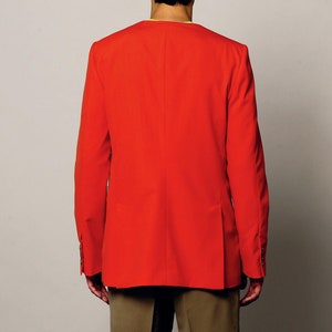 K&ouml;nnte beinhalten: Ein roter Blazer mit langen &Auml;rmeln und einem einzigen Knopfverschluss. Der Blazer wird &uuml;ber einem gelben Hemd und einer braunen Shorts getragen.
