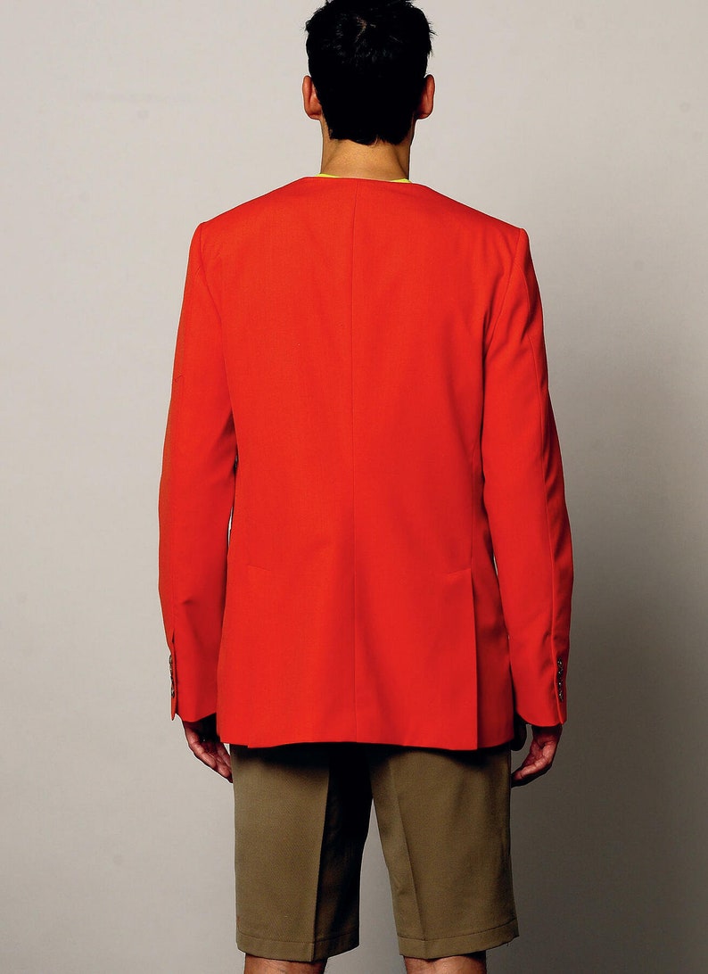 K&ouml;nnte beinhalten: Ein roter Blazer mit langen &Auml;rmeln und einem einzigen Knopfverschluss. Der Blazer wird &uuml;ber einem gelben Hemd und einer braunen Shorts getragen.