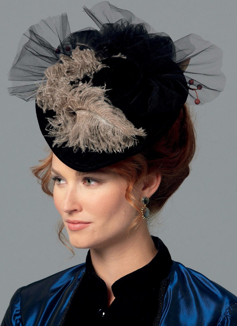 May include: A black velvet hat with a decorative arrangement of feathers and tulle. The hat features a wide brim and is adorned with a cluster of beige feathers and a delicate black tulle overlay. A vintage-inspired accessory.