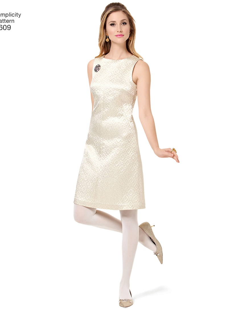 May include: A sleeveless white dress with a geometric pattern. The dress has a scoop neckline and a fitted silhouette. The model is wearing white tights and gold shoes.