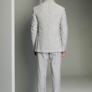 May include: A striped suit in a light blue and white color combination. The suit jacket has a single button closure and the pants have a straight leg.