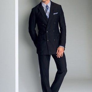 May include: A man wearing a black double-breasted suit jacket with a white shirt and a blue and white patterned tie. He is standing with his hands in his pockets.