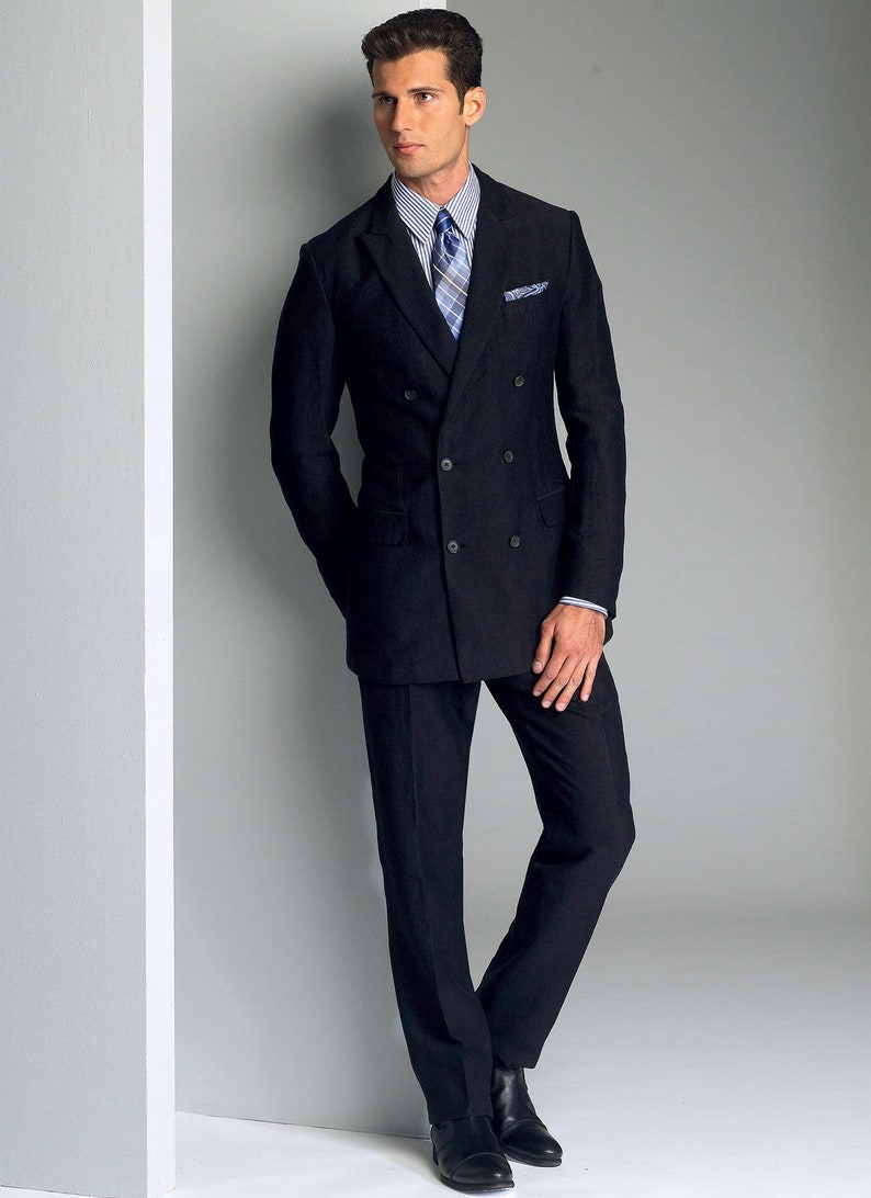 May include: A man wearing a black double-breasted suit jacket with a white shirt and a blue and white patterned tie. He is standing with his hands in his pockets.