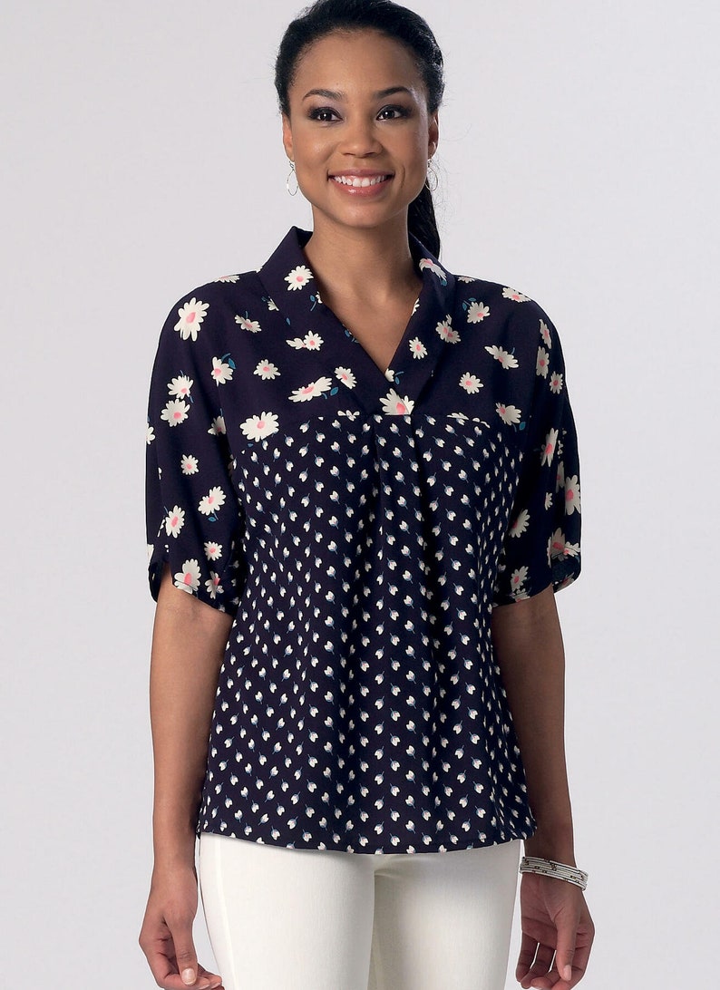 May include: A navy blue and white patterned blouse with a v-neck and short sleeves. The blouse has a floral pattern on the top half and a smaller white dot pattern on the bottom half.