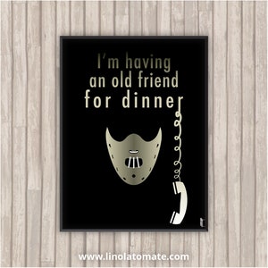 Peut inclure: Impression graphique noir et blanc avec le texte "I'm having an old friend for dinner." Un masque doré avec une chaîne et un téléphone blanc sont sur le côté droit de l'impression.