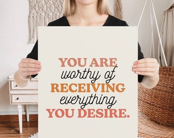 May include: A beige poster with the text "YOU ARE worthy of RECEIVING everything YOU DESIRE." in black and orange lettering.