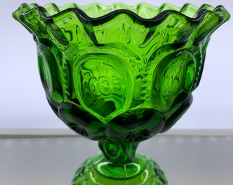 May include: A green glass candy dish with a scalloped rim and a pedestal base. The dish is decorated with a repeating pattern of stars and circles.