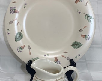 May include: A white ceramic pitcher with a floral design and a matching white ceramic plate with a floral design. The plate has a raised rim and the pitcher has a handle.