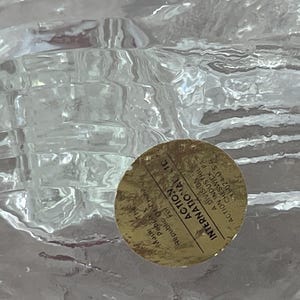 K&ouml;nnte beinhalten: Ein klares, strukturiertes Glasobjekt mit einem goldenen Aufkleber. Der Aufkleber tr&auml;gt die Aufschrift "ACTION INTERNATIONAL LIC" und enth&auml;lt Text &uuml;ber den Ursprung des Produkts in der Republik China.