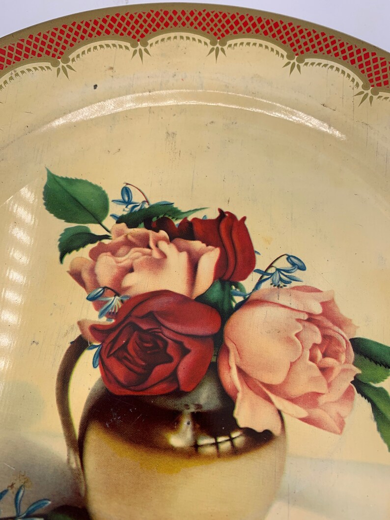 May include: A vintage tin tray with a red and gold border. The tray features a painted image of a bouquet of pink and red roses in a gold vase.