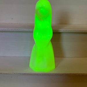 May include: A glowing green ceramic figurine of a woman with long hair and a flowing dress.