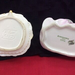 May include: Two vintage ceramic figurines, one white with a yellow floral design and the other pink with a floral design. The bottom of the white figurine has the text "Relco 5172" and the bottom of the pink figurine has the text "Samson Import Co. 1962 5296A".