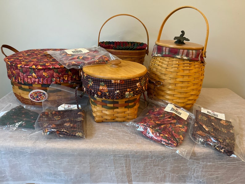 May include: A set of four woven baskets with lids and fabric liners. The baskets are in various sizes and shapes, and the liners are in a autumnal-themed print with red, orange, and brown colours.