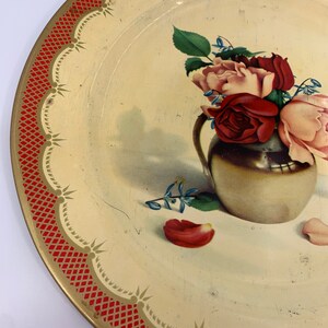 May include: A vintage metal serving tray with a red and gold border. The tray features a painted image of a bouquet of pink and red roses in a gold vase.