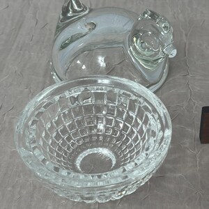 K&ouml;nnte beinhalten: Klarer Glasbeh&auml;lter in Schweineform mit Deckel und eine kleine, klare Glasschale mit einem strukturierten, gitterartigen Muster. Der Schweinebeh&auml;lter hat eine detaillierte Schnauze und Ohren. Die Sch&uuml;ssel ist rund und hat einen dekorativen Rand.