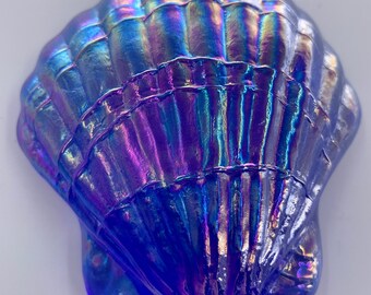May include: A blue iridescent glass seashell with a textured surface. The shell has a glossy finish and is shaped like a scallop.