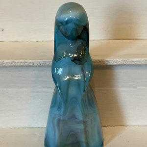 May include: A blue and white swirled glass figurine of a woman in a long dress.