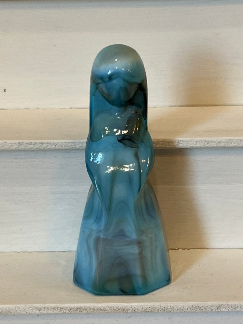 May include: A blue and white swirled glass figurine of a woman in a long dress.