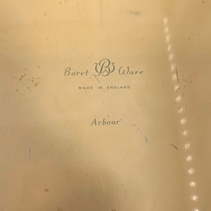 May include: A cream-colored metal tray with the text "Baret B Ware Made in England Arbour" printed on the bottom.