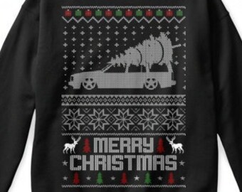 May include: Black Christmas sweater with a white silhouette of a car carrying a Christmas tree. The sweater has a red, green, and white snowflake pattern and the text "Merry Christmas".