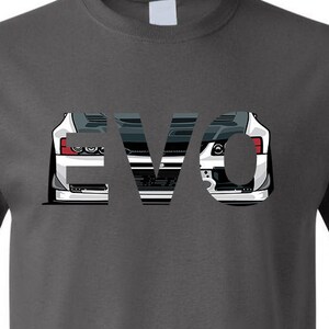May include: A dark grey t-shirt featuring a white graphic of a car's front end, the word "EVO" is formed by the car's headlights and grille.