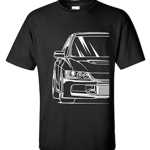 May include: Black t-shirt featuring a white outline of a car, showing a front view of the vehicle's headlights and grille.