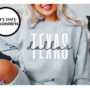May include: Gray sweatshirt with the text "Dallas Texas" in white and black lettering.
