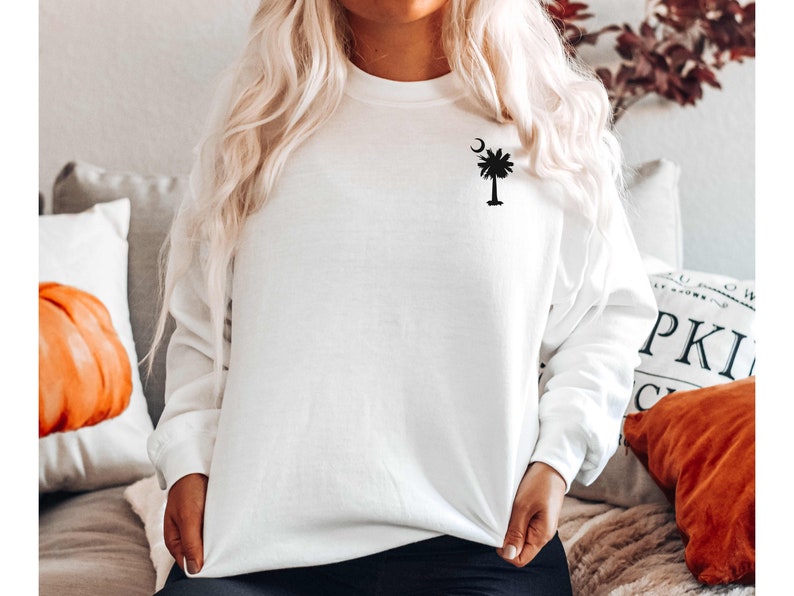 May include: White sweatshirt with a black palm tree and crescent moon design on the left chest.