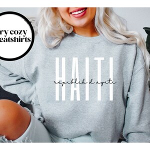 May include: Gray sweatshirt with white text that reads "HAITI" and "Repiblik d Ayiti" in a cursive font.