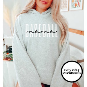 May include: Gray hooded sweatshirt with the text "Baseball mama" in white lettering. The sweatshirt is a cozy fit and has a relaxed, oversized look.