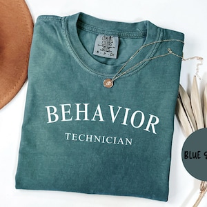 May include: A teal blue t-shirt with the text "BEHAVIOR TECHNICIAN" printed in white on the front. The shirt is made of a soft, comfortable material and has a vintage look.