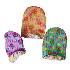 Puede incluir: Tres gorros con temática de gatos en tonos rosa, melocotón y verde azulado. Cada gorro presenta un patrón repetido de huellas de patas, ovillos de lana y el texto "Kitty Surprise". Los gorros tienen un patrón de rayas y un borde estampado.
