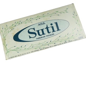 May include: A box of blue Sutil facial tissues. The box is decorated with a green floral pattern and the text "AZUL Sutil PAÑUELOS FACIALES". The box is made in Venezuela by C.A. Fabrica de Papel de Maracay.
