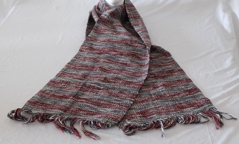 Striped, hand-woven scarf made of tree and virgin wool in anthracite/white and burgundy/white.